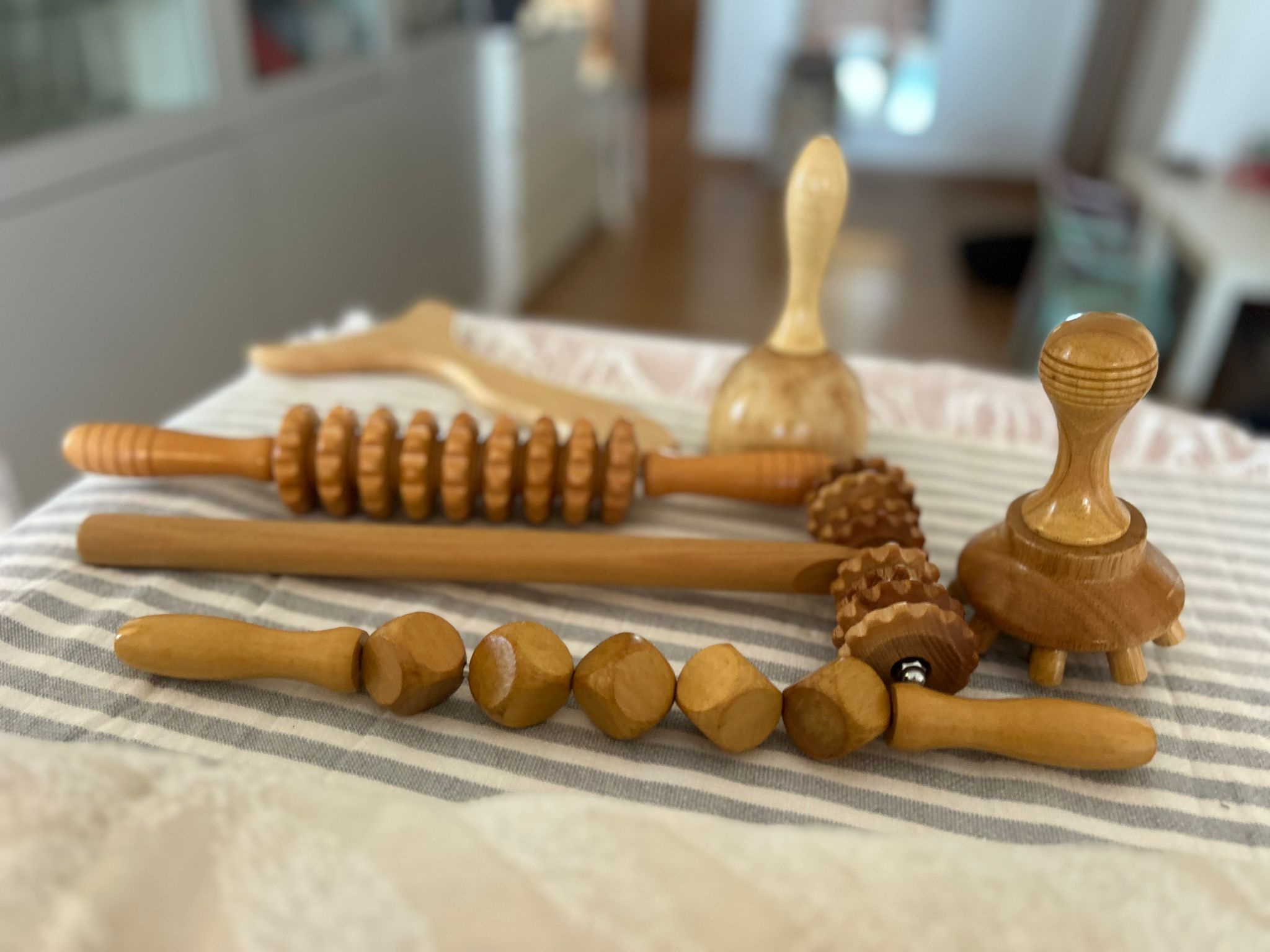 Conjunto de herramientas de madera artesanales para maderoterapia sobre una toalla de rayas